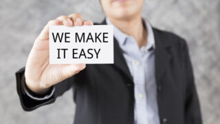 Businessman holding a card with the text -we make it easy- printed on it